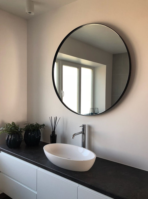 Round black mirror over sink
